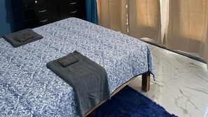 A bedroom with a bed, a dresser, a mirror, and a window with curtains. - Sea Breeze Studio At Carib Resort (Ocho Rios)