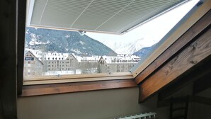 A skylight with a view of snow-covered mountains and buildings.