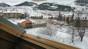A view from a window overlooking a snowy landscape with buildings and mountains.