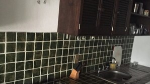 A kitchen with dark wooden cabinets, a black tiled backsplash, and a white stove. - Condo Alamandra by TRVL2HM (Nuevo Nayarit)