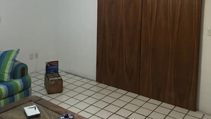 A room with a ceiling fan, a wooden wardrobe, a striped sofa, and a small table with a box and a remote control. - Condo Alamandra by TRVL2HM (Nuevo Nayarit)