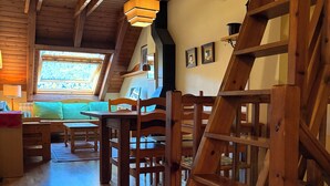 Un intérieur en bois avec une pièce aménagée dans le style d’un loft, un coin repas et un escalier.
