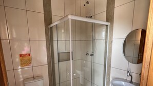 A bathroom with a glass-enclosed shower, a toilet, and a sink. - Pousada Rosália (Penha)