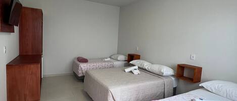 A room with three beds, a wooden cabinet, and a ceiling light.