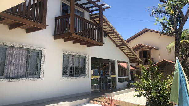A two-story building with a balcony, large windows, and a covered outdoor seating area. - Pousada Rosália (Penha)