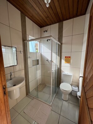 Une salle de bain avec une douche à parois de verre, un lavabo et des toilettes.