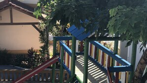A playground with a slide, climbing net, and wooden steps. - Pousada Rosália (Penha)