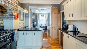 A kitchen with a central island, a stove, cabinets, and a clock on the wall.