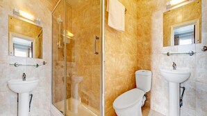 Ein Badezimmer mit zwei Waschbecken, einer Toilette und einer Duschkabine.
