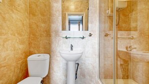 Ein Badezimmer mit Toilette, Waschbecken und Duschkabine aus Glas.