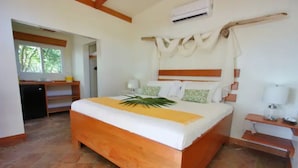 Une chambre avec un lit en bois, un bureau et une chaise. Il y a une fenêtre donnant sur des arbres.