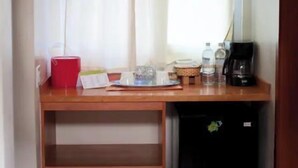 Une petite cuisine équipée d’un plan de travail en bois, d’un réfrigérateur et d’une fenêtre avec des rideaux.