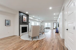 A spacious living area with a fireplace, a round rug, and a seating area.