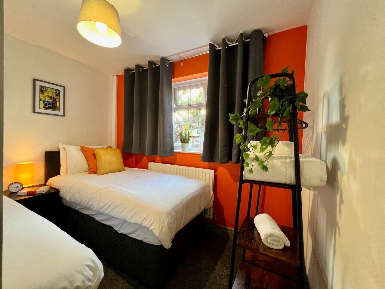 Ein Hotelzimmer mit Bett, Nachttisch, Lampe und Pflanze.