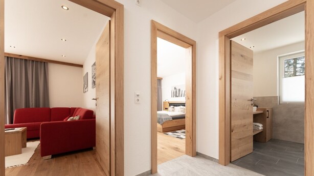 A modern apartment with a red sofa, a bed, and a bathroom with a window.