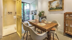 Un comedor moderno con una mesa de madera, sillas blancas y un aparador de vidrio con copas de vino.