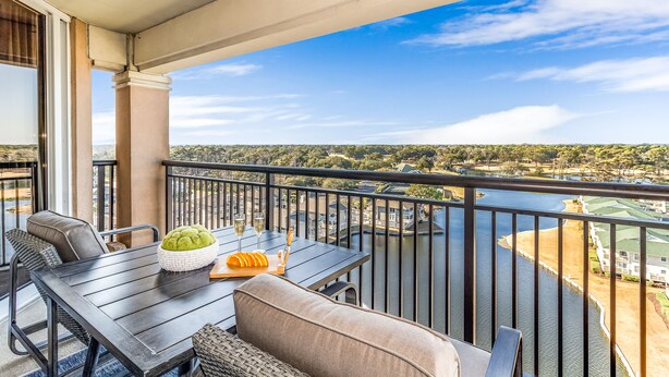 A balcony with a table, chairs, and a view of a river and distant buildings. - Cozy N. Myrtle Beach Condo w/ access to resort amenities. Short Walk to Beach.   (North Myrtle Beach)