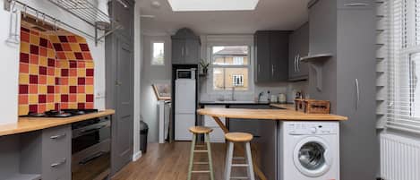 A modern kitchen with a central island, built-in appliances, and a view to the outside.
