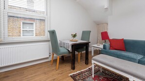 Una sala de estar moderna con comedor, un sofá azul y una lámpara roja.