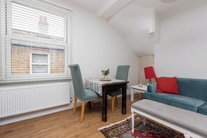 A modern living room with a dining area, a blue sofa, and a red lamp.
