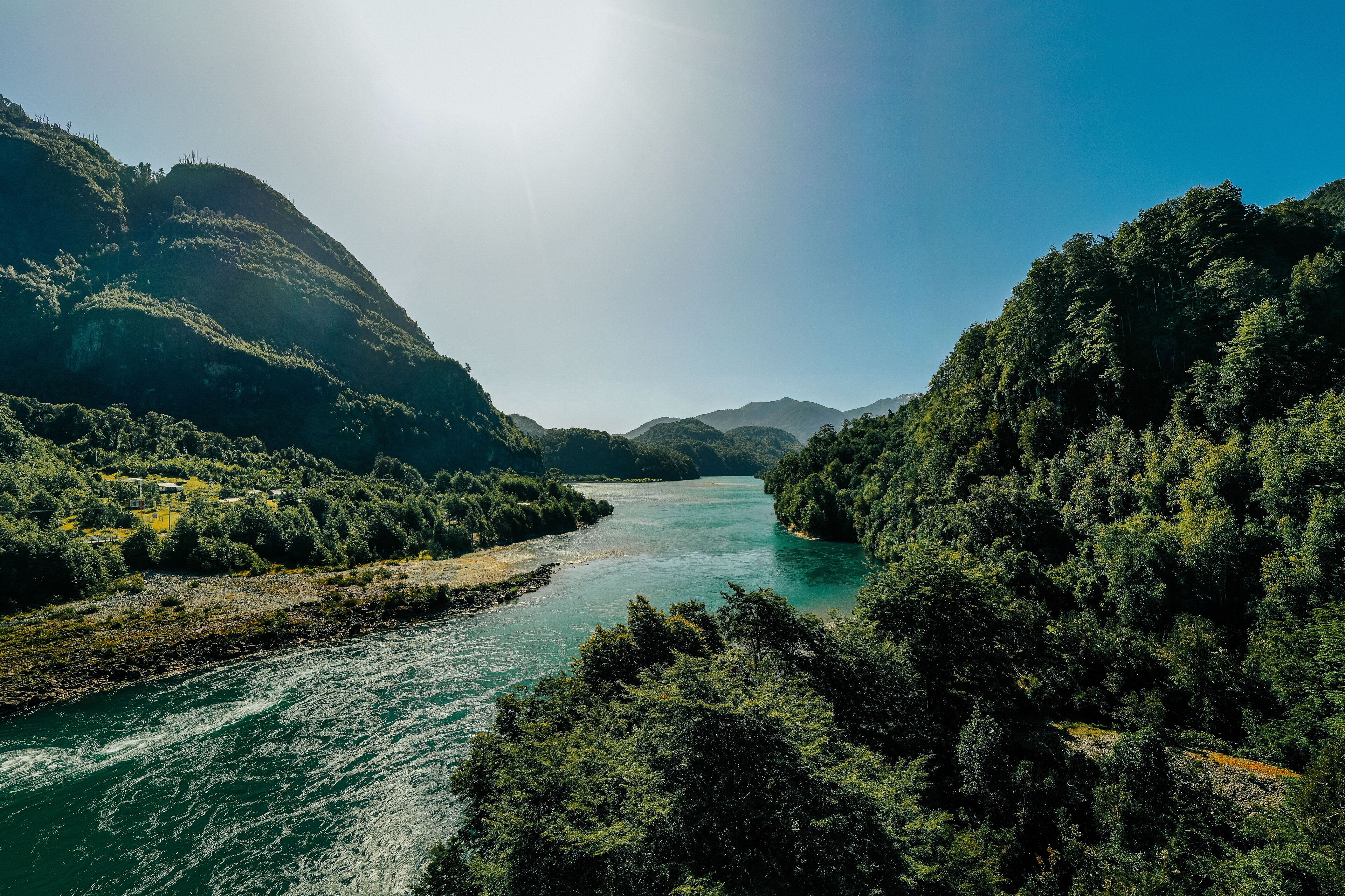 A river flowing through a forested valley with hills on either side.