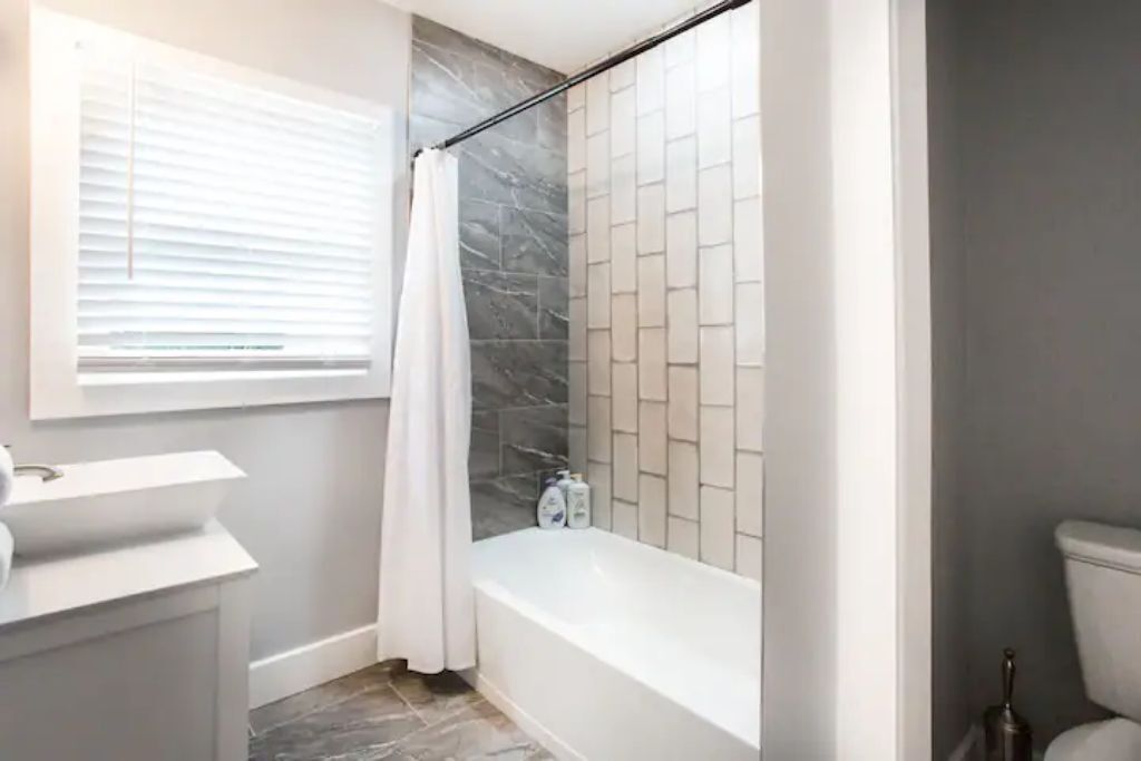 Une salle de bain avec une baignoire, un rideau de douche et des murs carrelés.