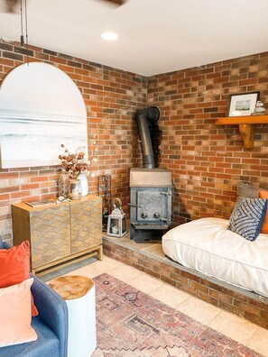 Una sala de estar acogedora con pared de ladrillo, chimenea, sofá, mesa de centro y estante decorativo.