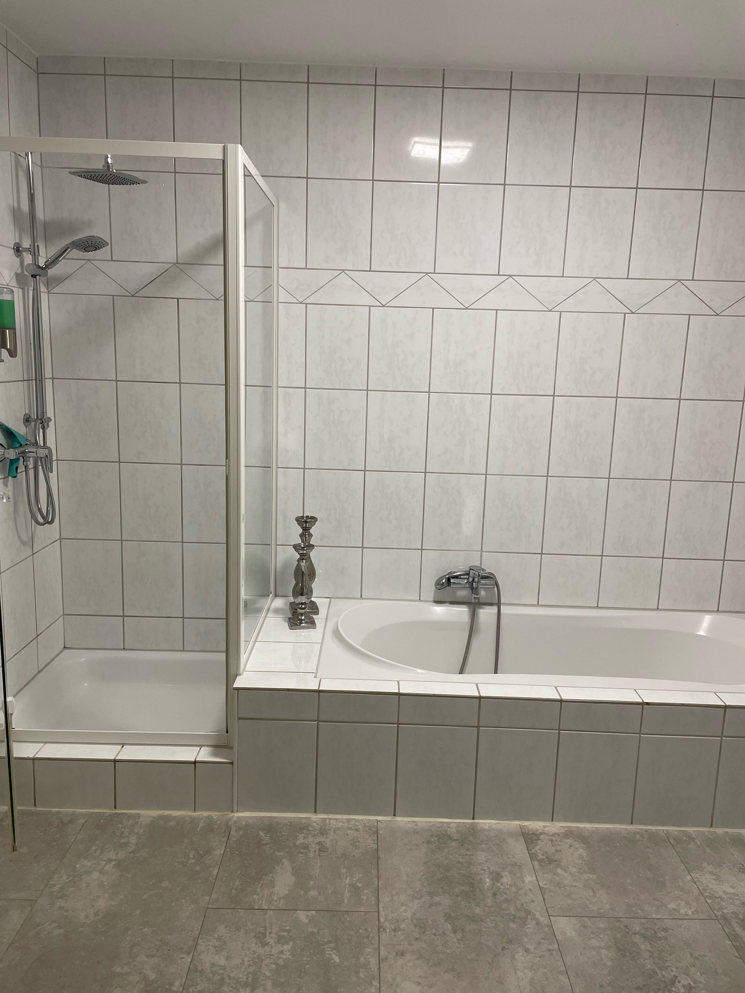 Un baño con ducha a nivel, bañera y paredes de azulejos.