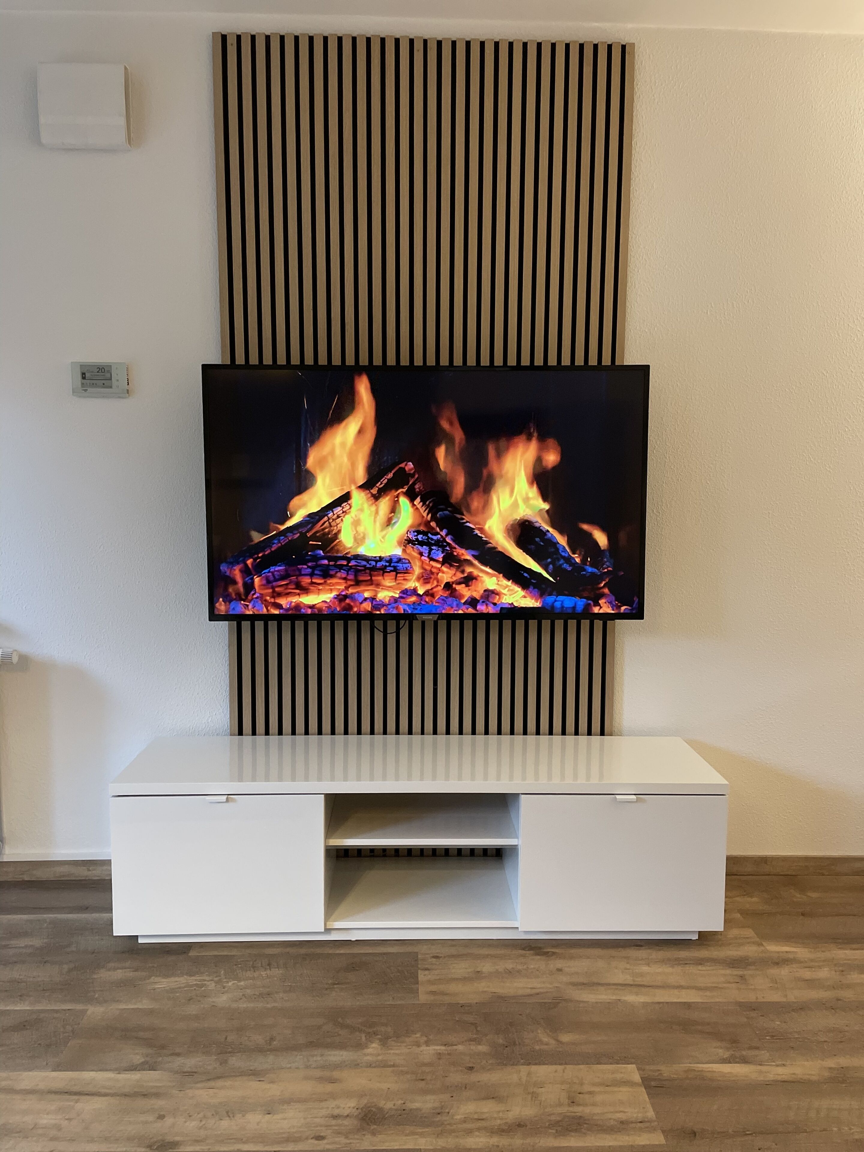 A flat-screen TV mounted on a wall above a white entertainment unit.