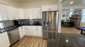A modern kitchen with white cabinets, stainless steel appliances, and a marble countertop.