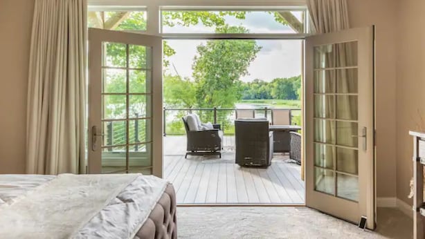 Ein Schlafzimmer mit einer großen Schiebeglasdoor zum Außenbereich mit einer Sitzecke und einem Tisch.