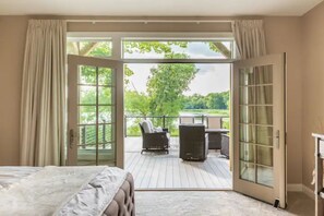 Ein Schlafzimmer mit einer großen Schiebeglasdoor zum Außenbereich mit einer Sitzecke und einem Tisch.