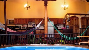 A pool area with a hammock, wooden cabinets, and a kitchen in the background. - You’ll know that you have rented a historic colonial home when you pass through huge, antique front doors framed by 3 foot-thick adobe walls. Lounge on the shallow, submerged bench seats in the pool or in the hammocks hanging between 12 foot wooden c (Granada)
