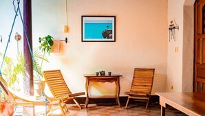 A room with a checkered floor, two wooden chairs, a small table with a teapot, a framed picture on the wall, and a hanging plant. - You’ll know that you have rented a historic colonial home when you pass through huge, antique front doors framed by 3 foot-thick adobe walls. Lounge on the shallow, submerged bench seats in the pool or in the hammocks hanging between 12 foot wooden c (Granada)