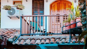 A two-story building with a tiled roof, wooden balconies, and potted plants. - You’ll know that you have rented a historic colonial home when you pass through huge, antique front doors framed by 3 foot-thick adobe walls. Lounge on the shallow, submerged bench seats in the pool or in the hammocks hanging between 12 foot wooden c (Granada)