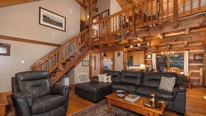 A spacious living room with a high wooden ceiling, a staircase, leather sofas, and a coffee table. - Hounds Retreat Pet Friendly, Wood Fireplace, HotTub, WiFi, Decks (Ferguson)