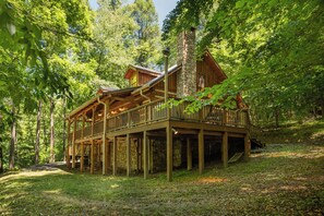 A wooden cabin with a stone chimney, surrounded by trees. - Hounds Retreat Pet Friendly, Wood Fireplace, HotTub, WiFi, Decks (Ferguson)