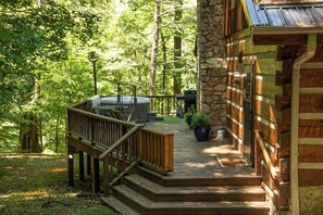 A wooden deck with a hot tub, outdoor seating, and potted plants.