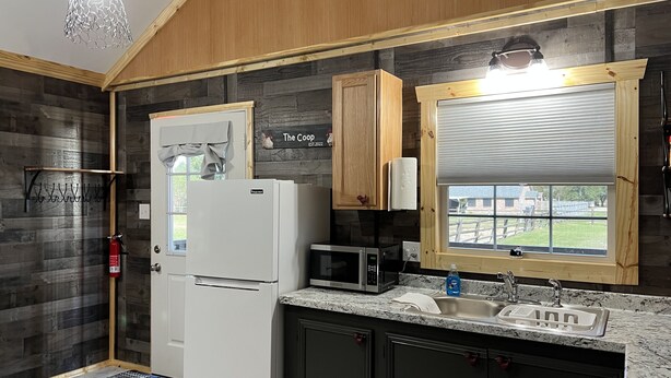 A compact kitchen with a refrigerator, microwave, and sink. - The Coop.  A lil taste of country with horses and chickens. (Scott)