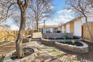 Il s’agit d’une propriété résidentielle dotée d’un patio dallé, d’une clôture en bois et d’un jardin aménagé avec des plates-bandes surélevées.