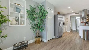 A modern kitchen with a built-in refrigerator, a dining area with a bench, and a potted plant.