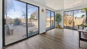 A spacious room with large sliding glass doors leading to an outdoor patio, a wooden floor, and a star-shaped decoration on the wall.