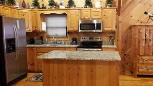 A kitchen with wooden cabinets, a stainless steel refrigerator, a microwave, and a stove.
