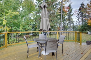 A wooden deck with a round table and chairs, surrounded by a yellow railing. - Elcho Escape w/ Private Dock on Post Lake! (Elcho)