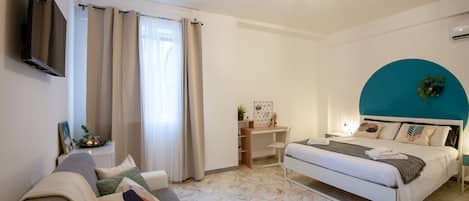 A modern bedroom with a bed, a desk, and a sofa.