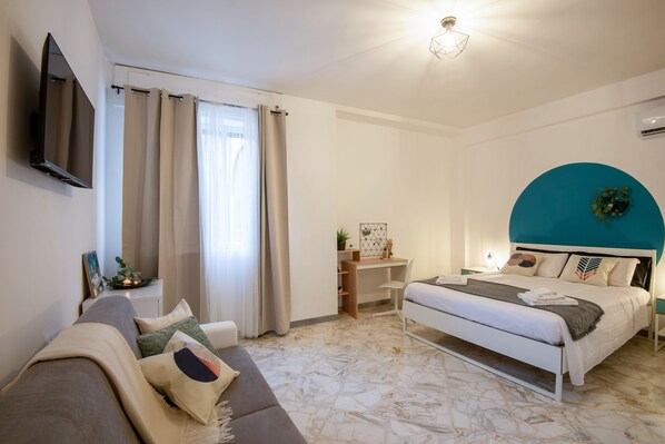 A modern bedroom with a bed, a desk, and a sofa.