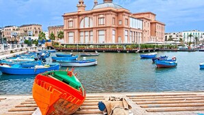 A waterfront with boats docked and a prominent pink building in the background. - [Central Station ★★★★★] Elegant Apartment (BARI)