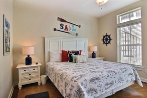 A bedroom with a sail-themed bedspread, a captain's wheel, and a 'Sail' sign above the bed.