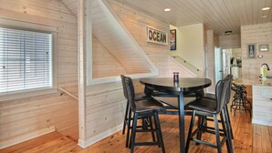 Een eethoek met een ronde tafel en vier stoelen, een houten trap en een bord met daarop 'OCEAN' aan de muur.