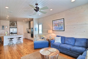 A spacious living area with a blue sofa, a wooden coffee table, and a kitchen in the background.